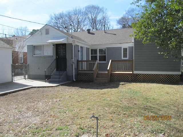 back of house with roof with shingles, a gate, fence, a yard, and brick siding