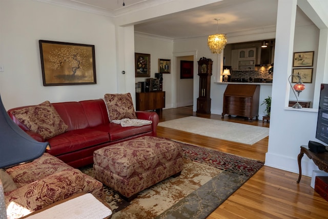 living room with a chandelier, baseboards, wood finished floors, and crown molding