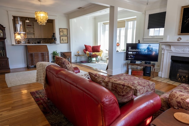 living room featuring light wood finished floors, a fireplace with flush hearth, and crown molding