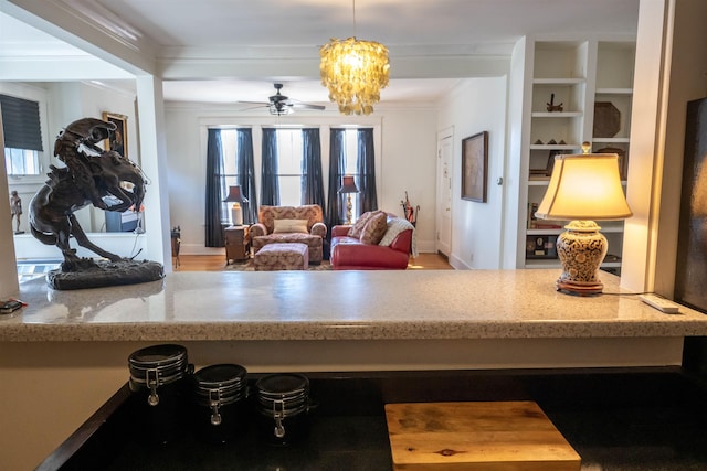 interior space with ornamental molding and ceiling fan with notable chandelier