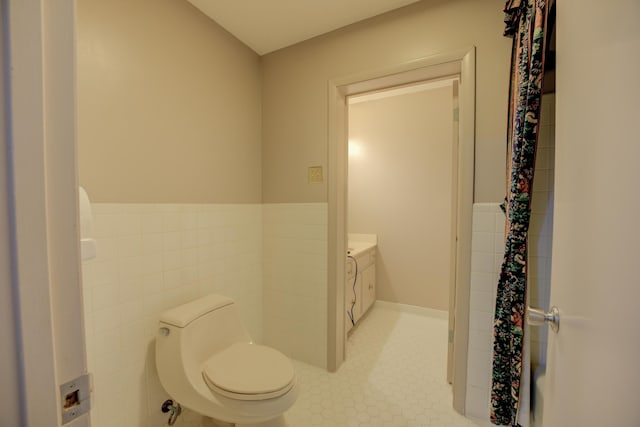 bathroom featuring vanity, toilet, and tile walls