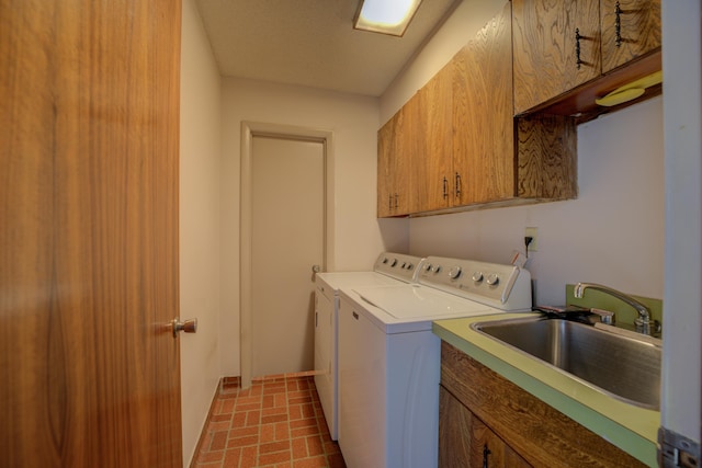 clothes washing area featuring brick floor, cabinet space, separate washer and dryer, and a sink