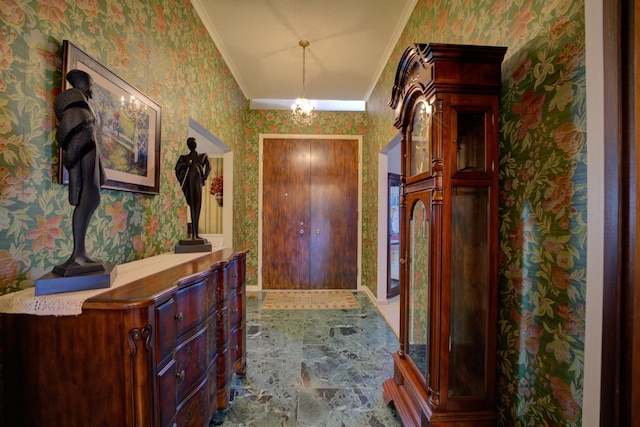 foyer with a chandelier, ornamental molding, stone finish floor, and wallpapered walls