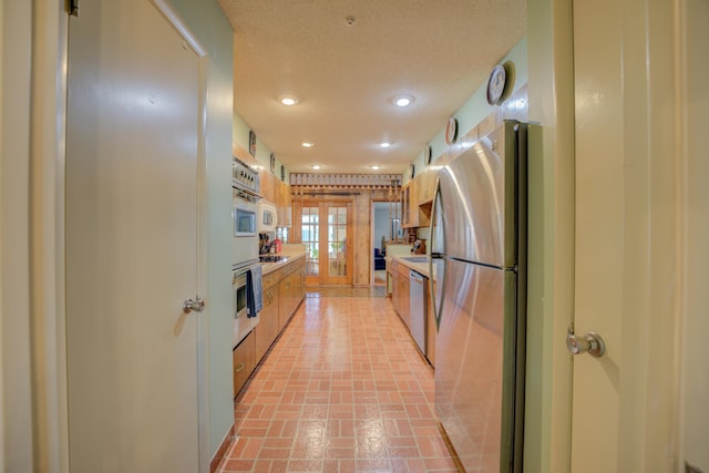 kitchen with brick floor, recessed lighting, light countertops, appliances with stainless steel finishes, and a textured ceiling