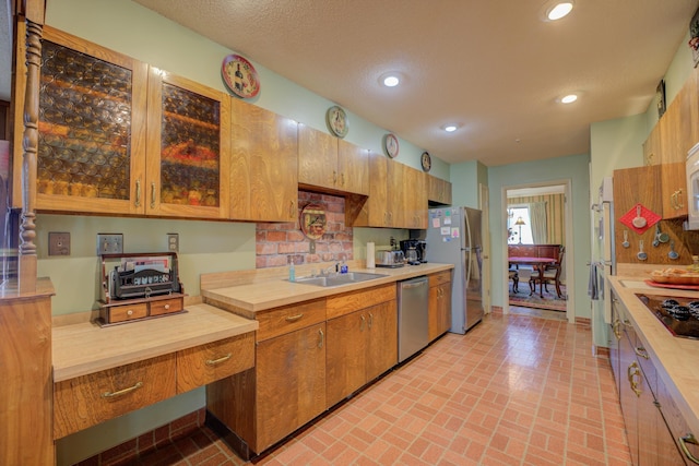 kitchen featuring appliances with stainless steel finishes, brown cabinets, light countertops, and glass insert cabinets