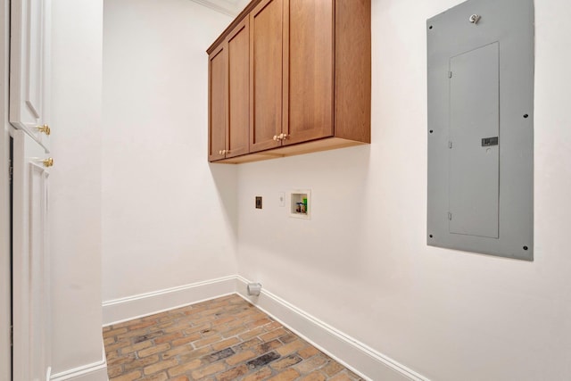 laundry area featuring cabinet space, electric panel, baseboards, brick floor, and washer hookup