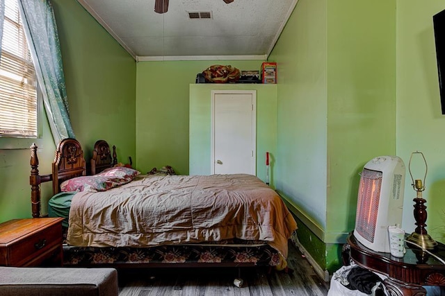 bedroom with ornamental molding, wood finished floors, visible vents, and a ceiling fan