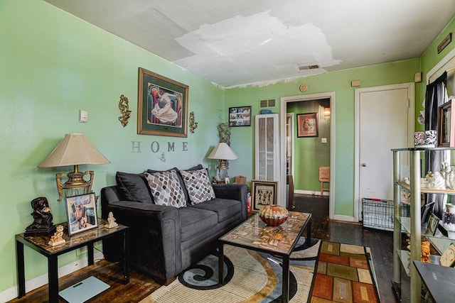 living room with dark wood-style floors, visible vents, and baseboards