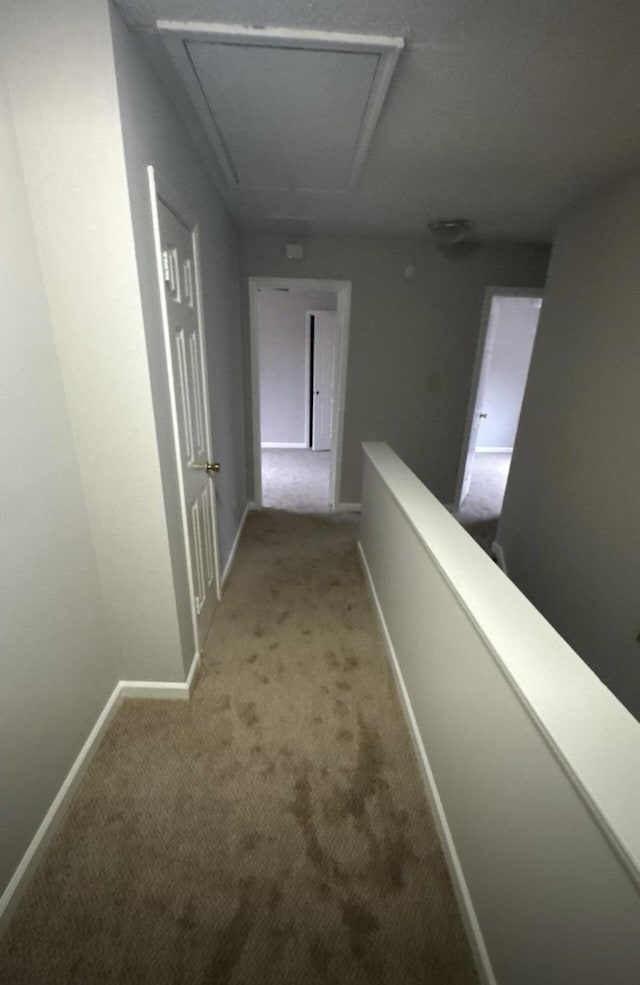 corridor featuring carpet, baseboards, and an upstairs landing