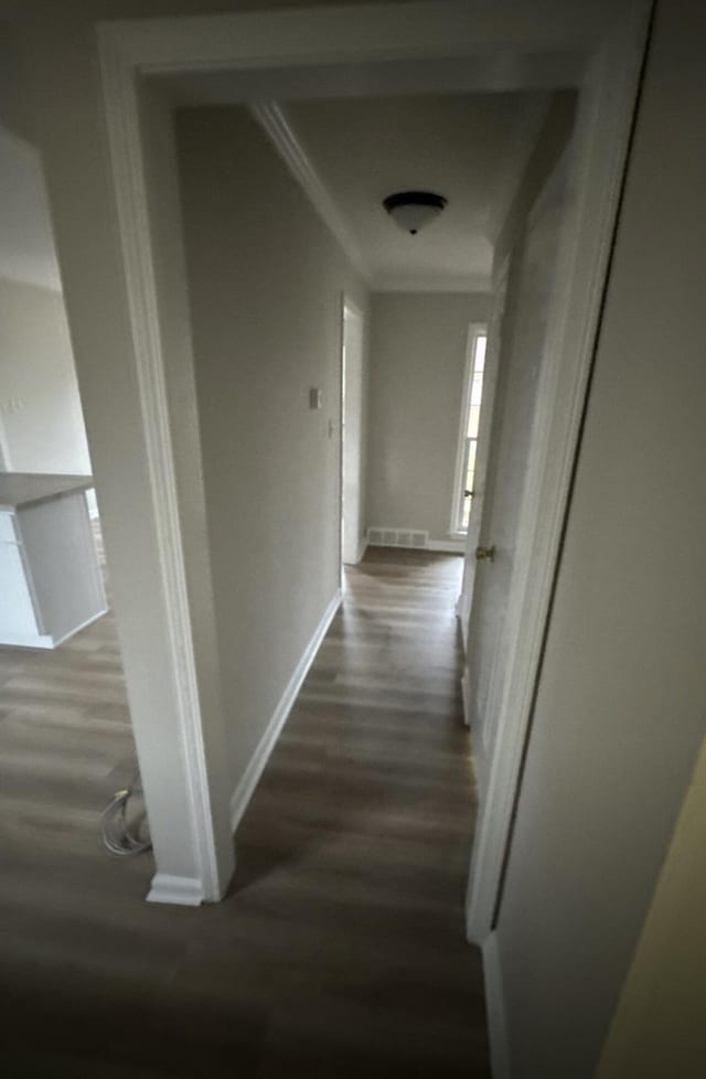 hall featuring ornamental molding, dark wood finished floors, and baseboards