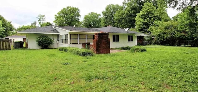 rear view of house featuring a lawn and stucco siding