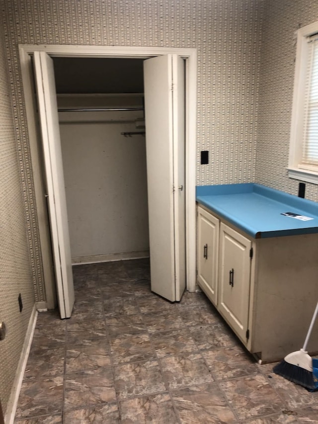 bathroom with wallpapered walls and stone finish flooring