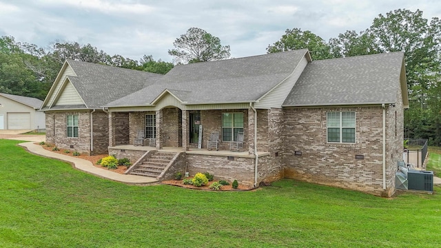 view of front of house featuring central AC unit, a porch, roof with shingles, and a front yard