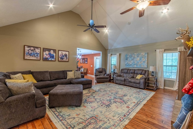 living room with high vaulted ceiling, light wood-type flooring, and baseboards