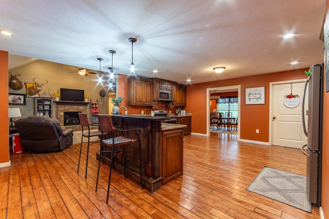 kitchen featuring stainless steel appliances, a breakfast bar, light wood-style floors, open floor plan, and brown cabinets