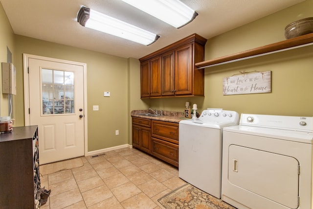 laundry area featuring light tile patterned floors, cabinet space, a sink, washer and dryer, and baseboards