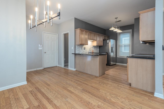 kitchen featuring dark countertops, visible vents, light wood-style floors, light brown cabinets, and stainless steel fridge