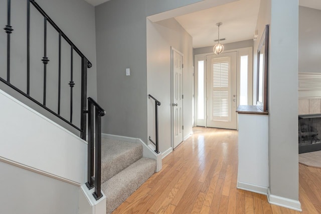 foyer entrance with baseboards, a fireplace, stairway, and hardwood / wood-style floors