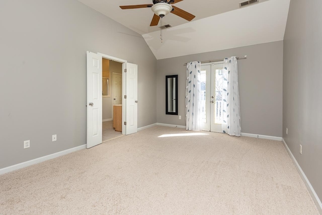 empty room featuring lofted ceiling, french doors, light carpet, and visible vents