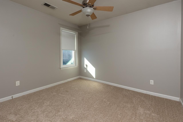 empty room featuring baseboards, ceiling fan, visible vents, and light colored carpet