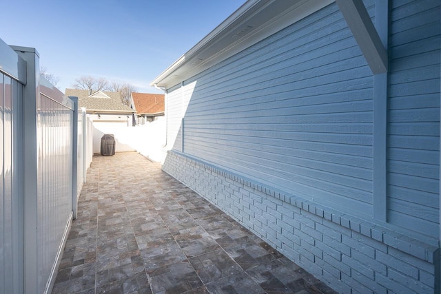 view of side of home featuring a patio area, a fenced backyard, and brick siding