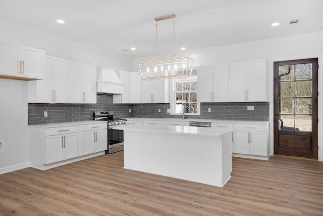 kitchen featuring stainless steel appliances, light countertops, premium range hood, and white cabinetry