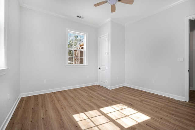 spare room with light wood-type flooring, visible vents, crown molding, and baseboards