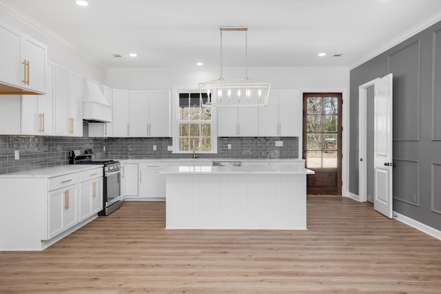 kitchen featuring white cabinets, decorative light fixtures, custom exhaust hood, stainless steel appliances, and light countertops