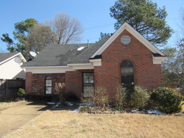 view of front facade featuring brick siding, a front lawn, a shingled roof, and fence