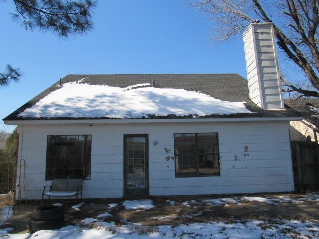 snow covered back of property with a chimney