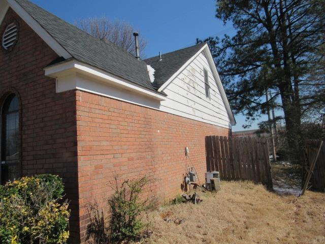 view of side of home featuring brick siding and a shingled roof