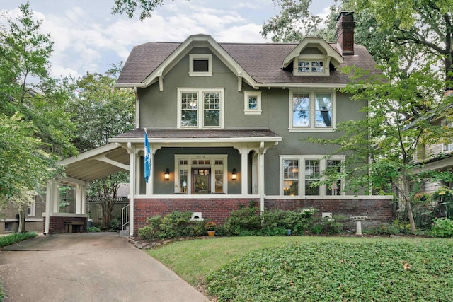 view of front of property featuring covered porch, brick siding, stucco siding, a chimney, and a front yard