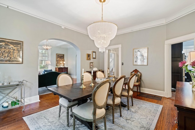 dining space featuring crown molding, dark wood-style flooring, and an inviting chandelier