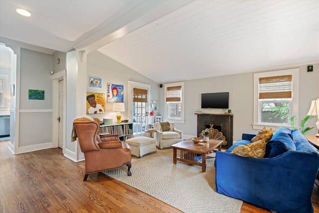 living room with lofted ceiling with beams, a fireplace, baseboards, and wood finished floors