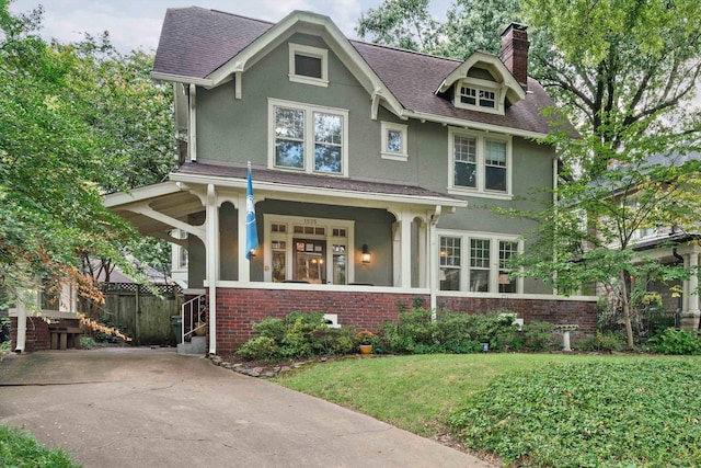 view of front of home with brick siding, stucco siding, a chimney, a porch, and a front yard