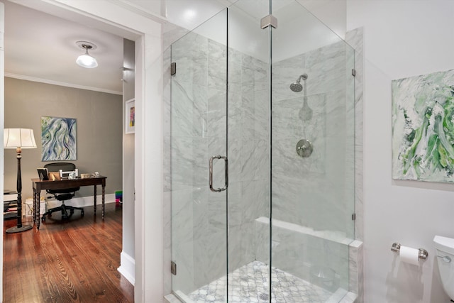 bathroom featuring crown molding, toilet, a shower stall, wood finished floors, and baseboards