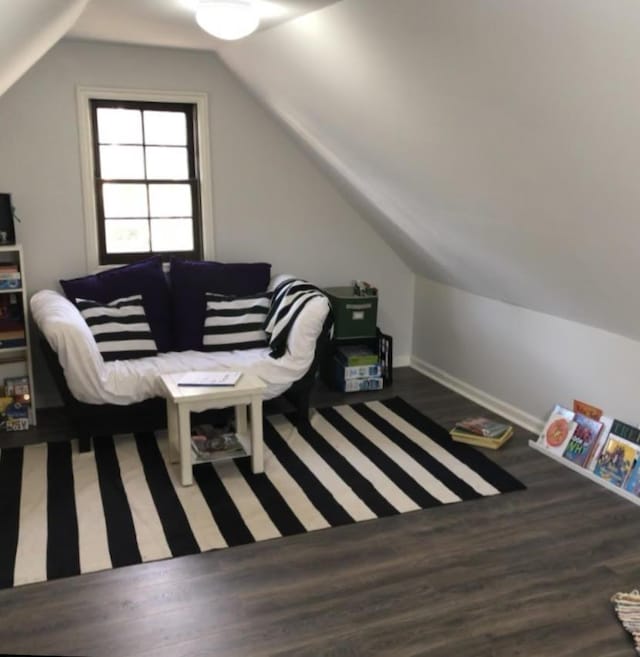 living area featuring baseboards, vaulted ceiling, and wood finished floors