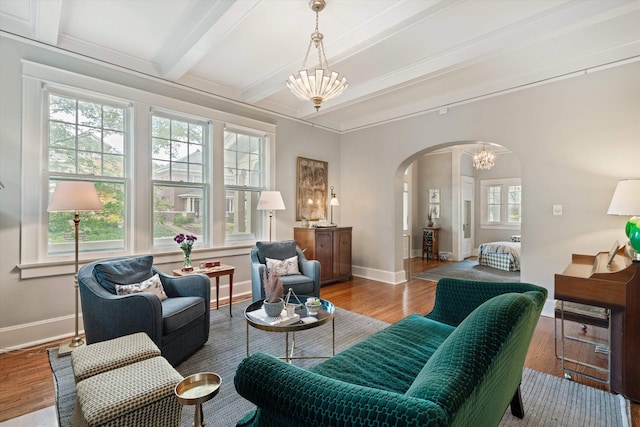 interior space featuring baseboards, arched walkways, wood finished floors, beamed ceiling, and an inviting chandelier