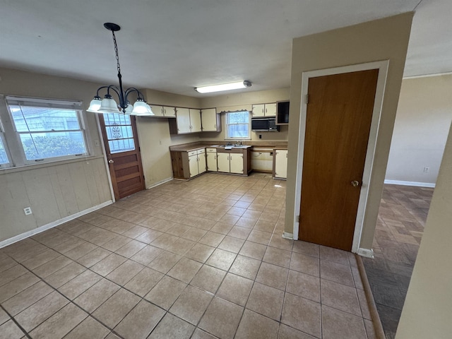 kitchen featuring black microwave, light tile patterned flooring, a notable chandelier, hanging light fixtures, and cream cabinetry