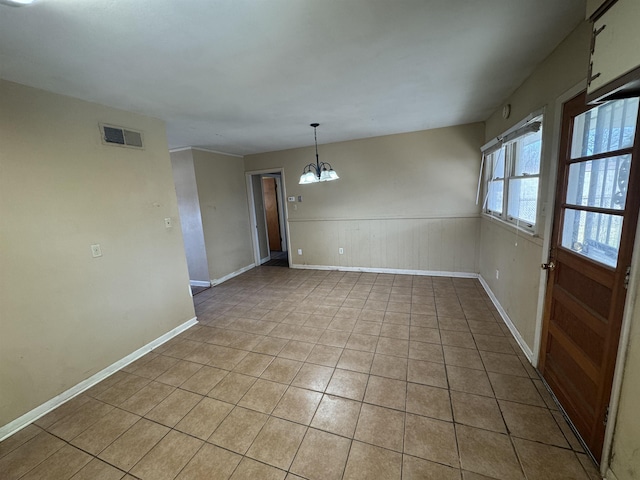 unfurnished dining area featuring a chandelier, light tile patterned floors, wainscoting, and visible vents