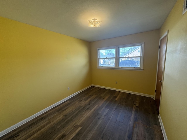 spare room featuring dark wood-type flooring, visible vents, and baseboards