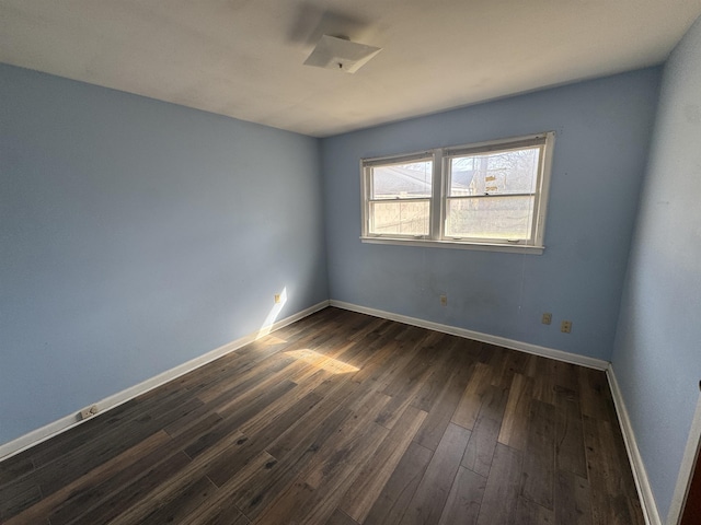 empty room with dark wood-type flooring and baseboards