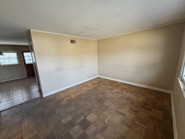 empty room featuring ornamental molding, visible vents, and baseboards