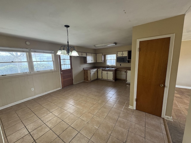 kitchen featuring black microwave, light tile patterned flooring, baseboards, decorative light fixtures, and an inviting chandelier