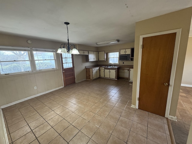 kitchen with a notable chandelier, light tile patterned floors, hanging light fixtures, a sink, and baseboards