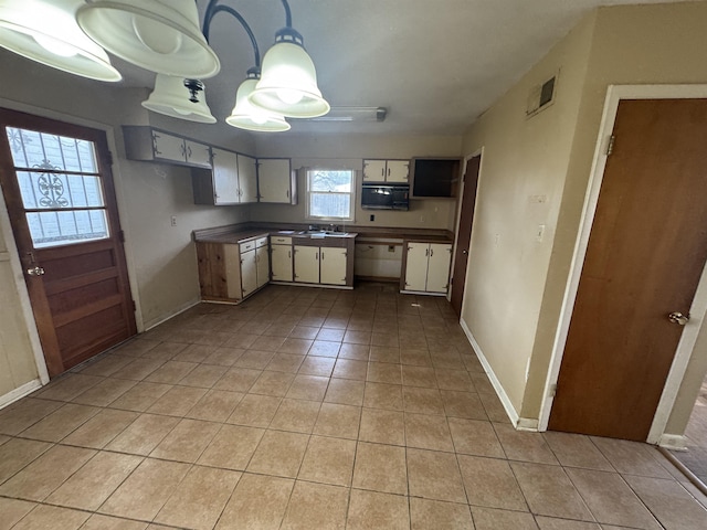 kitchen featuring dark countertops, light tile patterned floors, baseboards, and visible vents