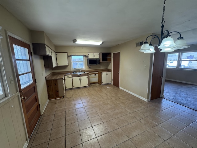 kitchen with black microwave, light tile patterned floors, decorative light fixtures, and baseboards