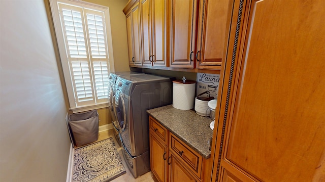 washroom with cabinet space, baseboards, and washer and dryer