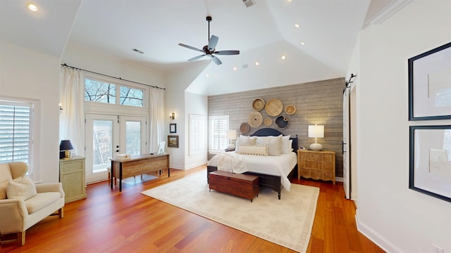 bedroom featuring visible vents, a barn door, wood finished floors, high vaulted ceiling, and access to outside