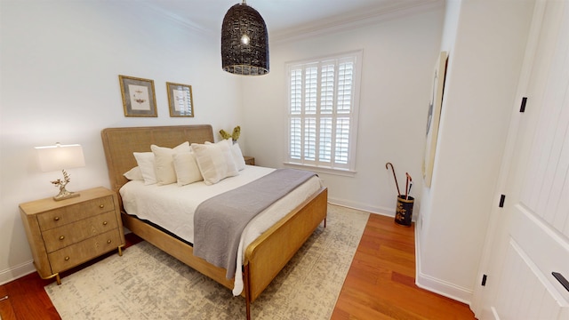 bedroom with crown molding, baseboards, and wood finished floors